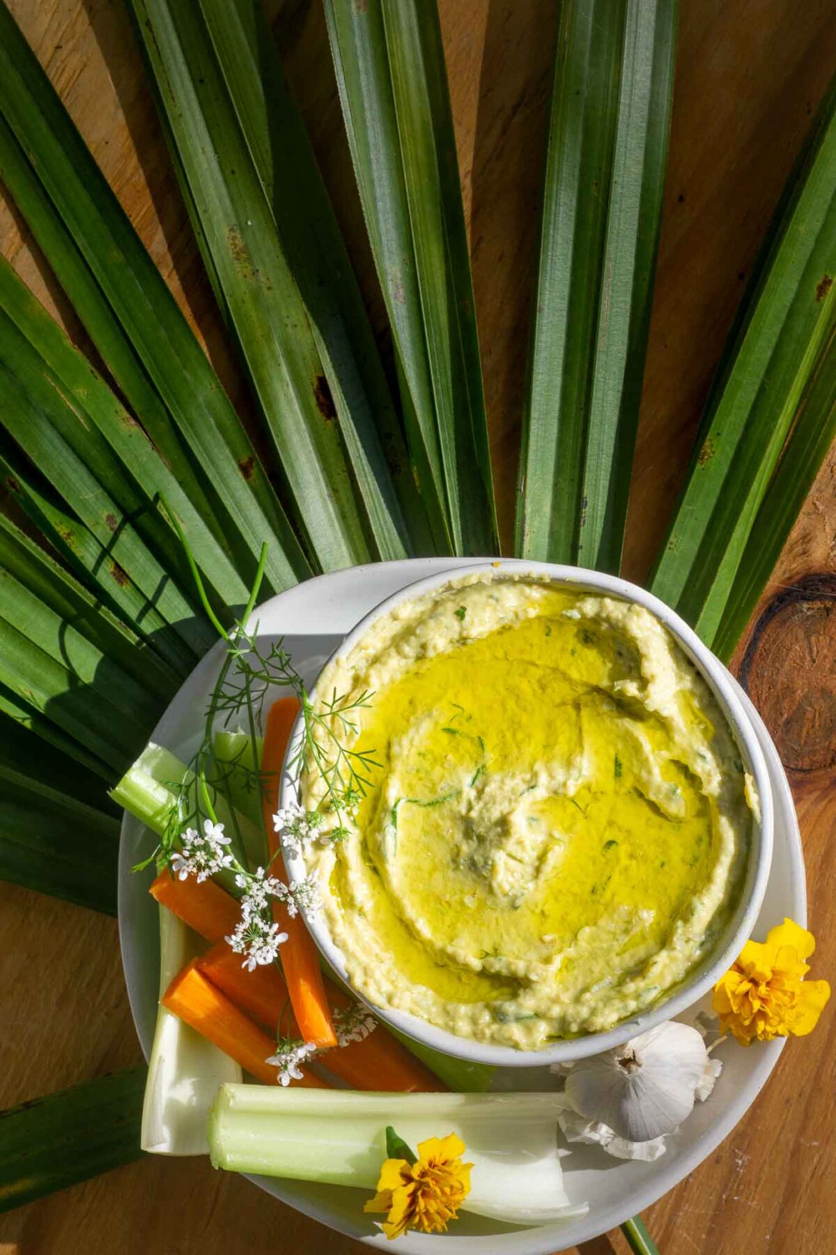 crudite and herb garden and avocado hummus on palm frond