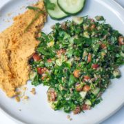 tabbouleh, hummus, and cucumbers on white plate