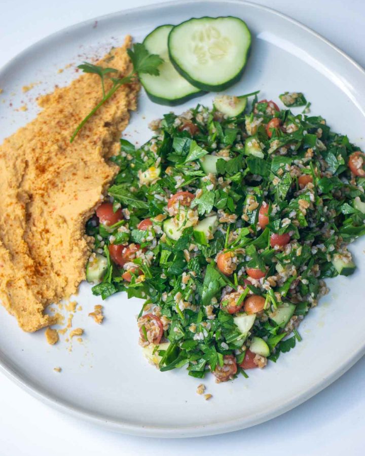 tabbouleh, hummus, and cucumbers on white plate