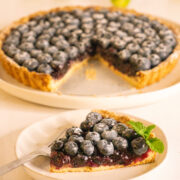 a slice of blueberry tart in front of the whole blueberry tart